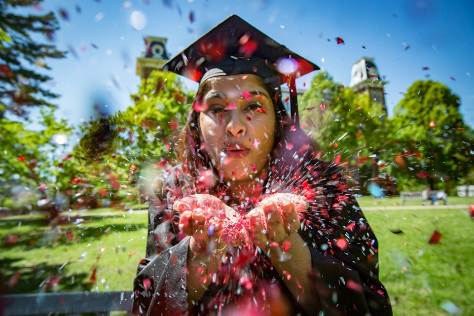 Graduate Blowing Confetti at the camera