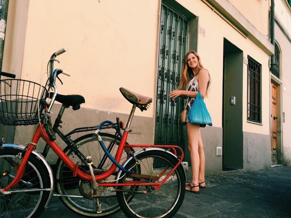 Girl entering door near red and blue bikes in a street abroad
